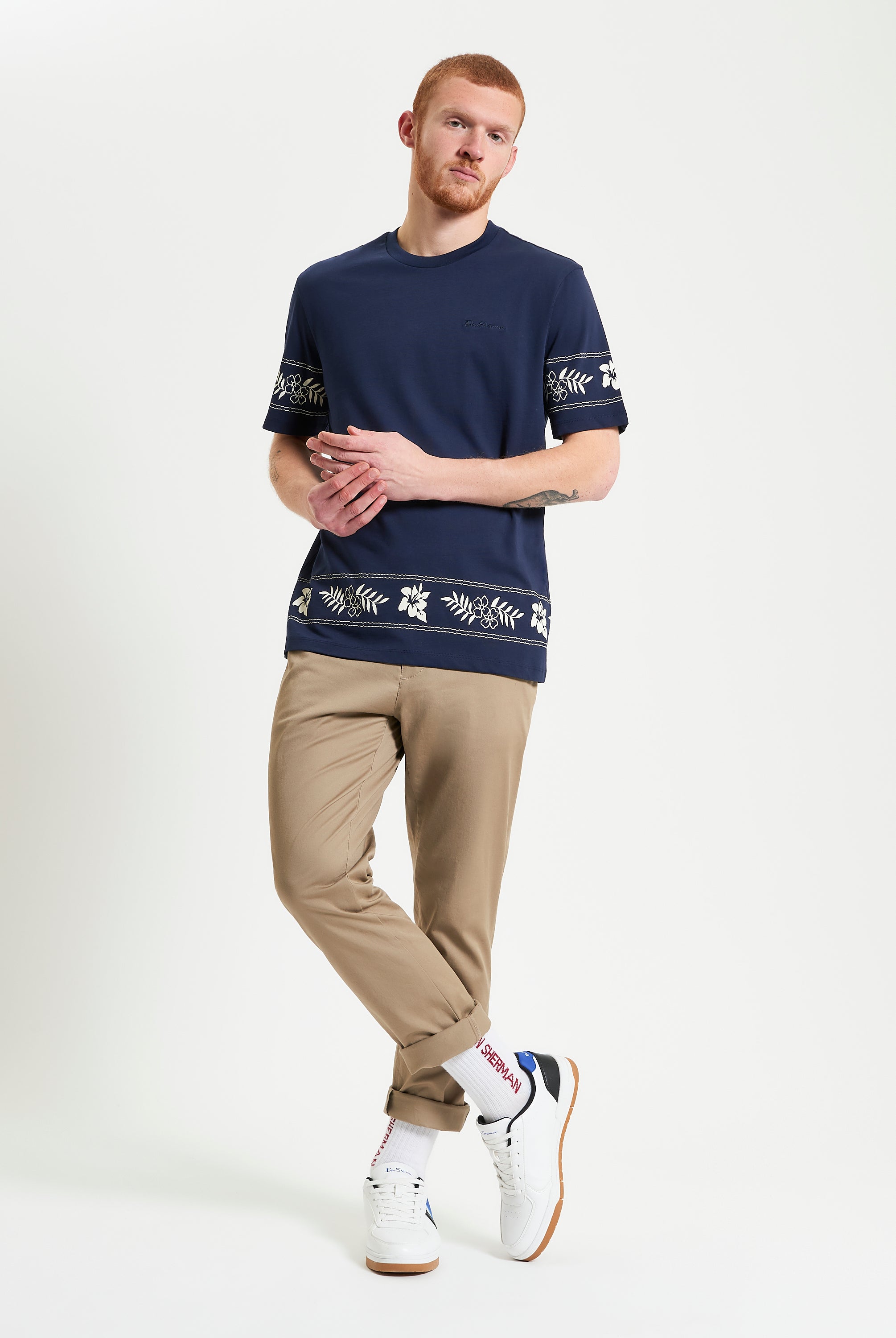Border Print Tee – navy blue with floral border print worn with light khaki pants.