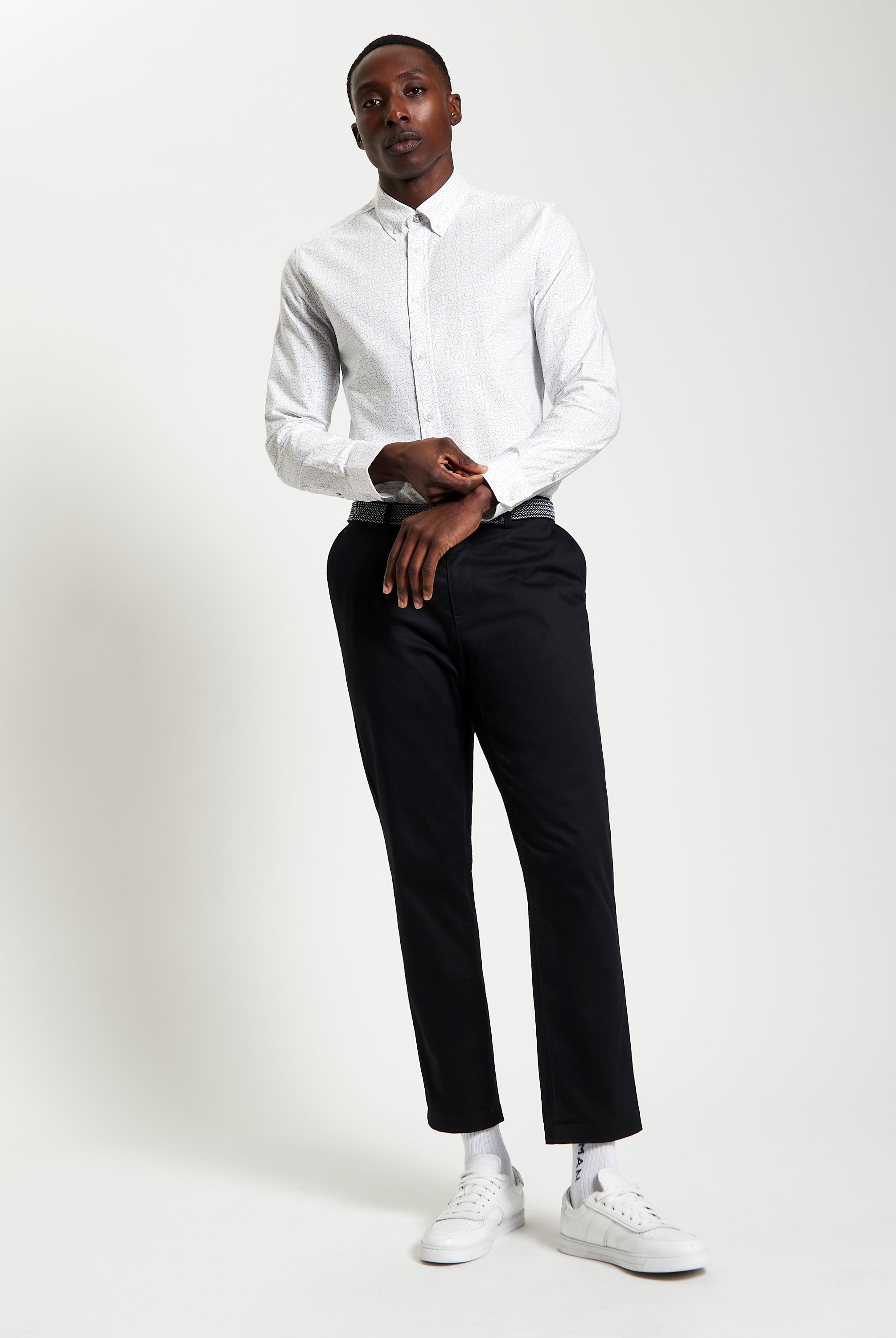 Stylish model showcasing Stipple Spot Print long sleeve shirt with black trousers and white sneakers.