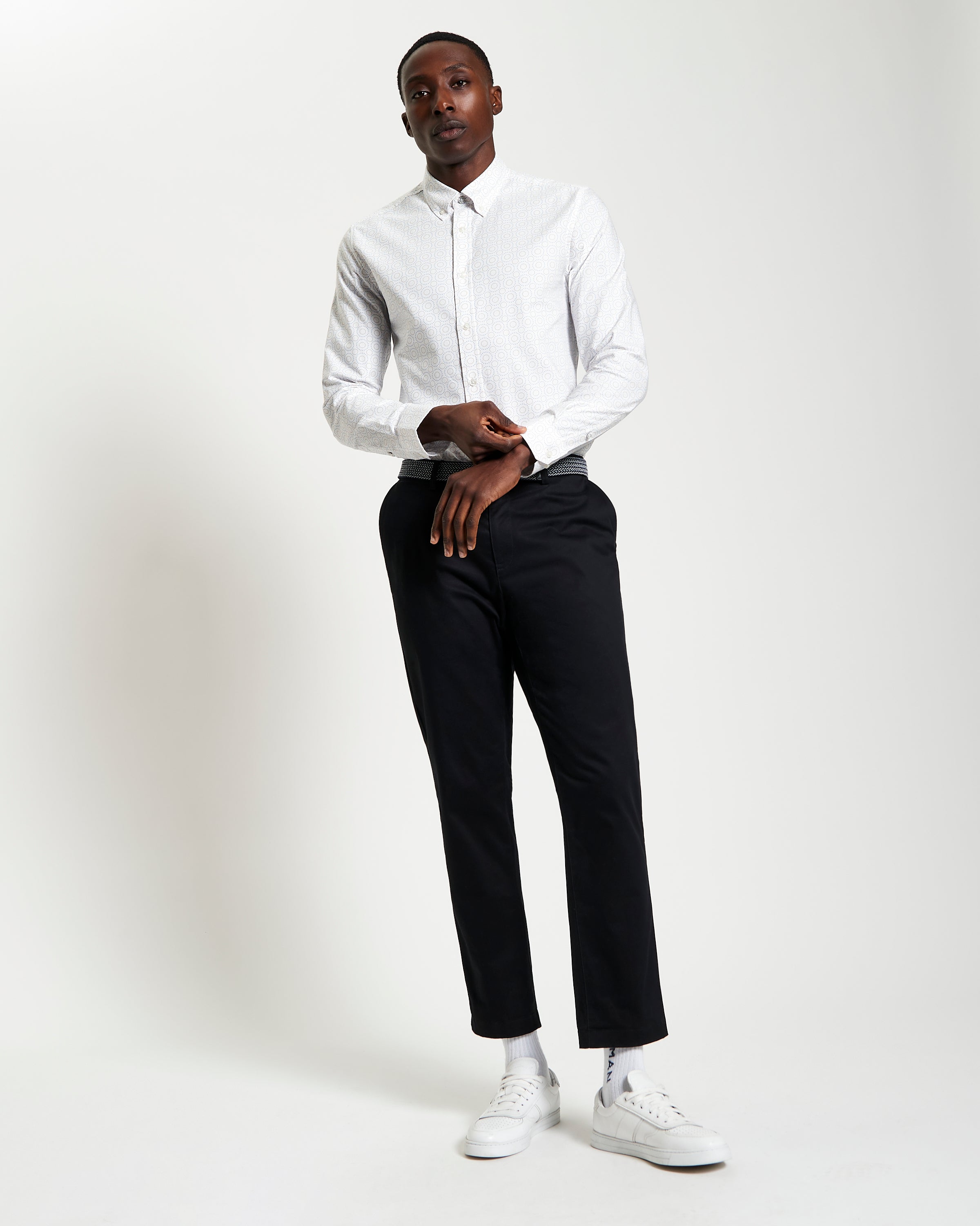 Stylish model showcasing Stipple Spot Print long sleeve shirt with black trousers and white sneakers.