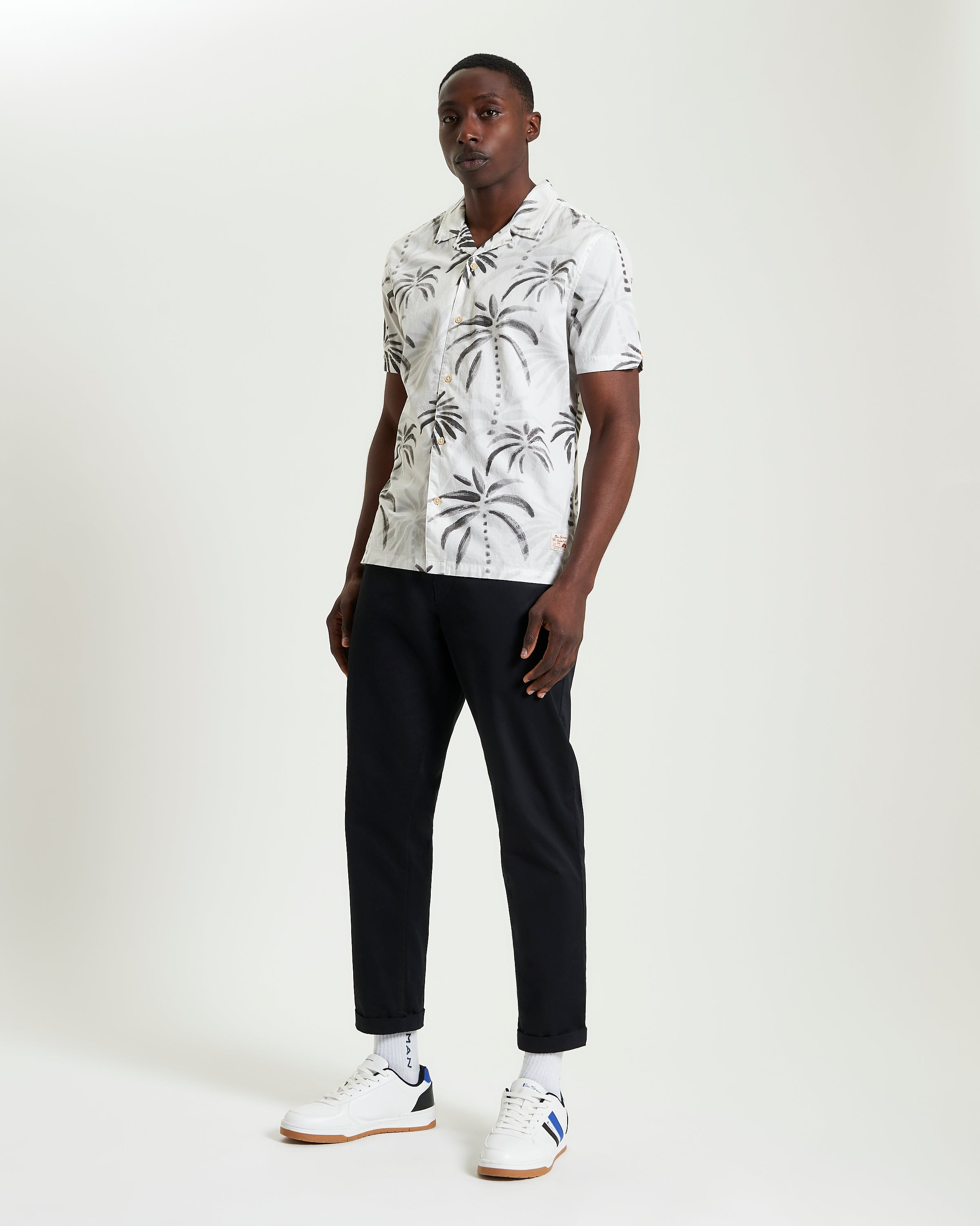 Palm Print Shirt featuring a relaxed collar, short sleeves, and styled with black pants and sneakers.