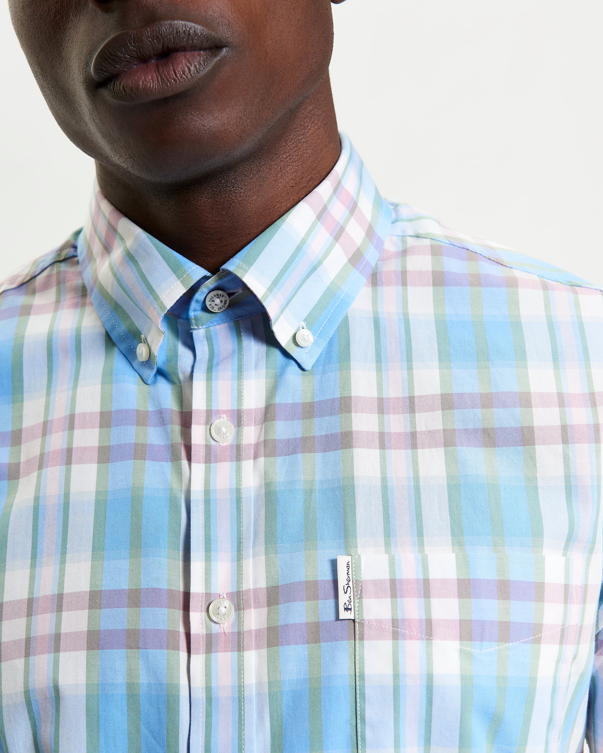 Irregular Check shirt featuring a three-finger button-down collar and curved hem, made from 100% organic cotton.