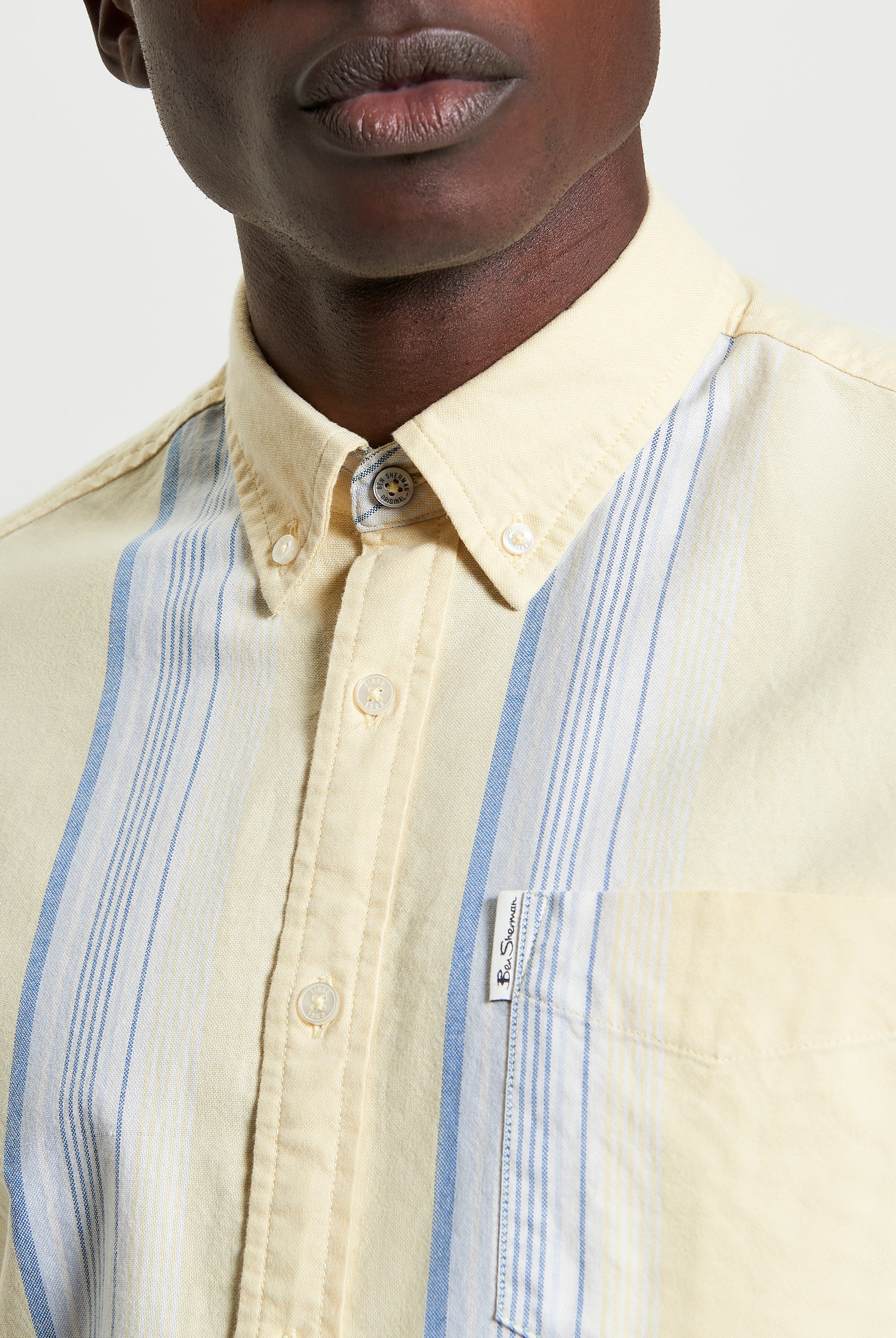 Oxford Stripe β Short sleeve shirt with blue and yellow stripes and chest pocket label.