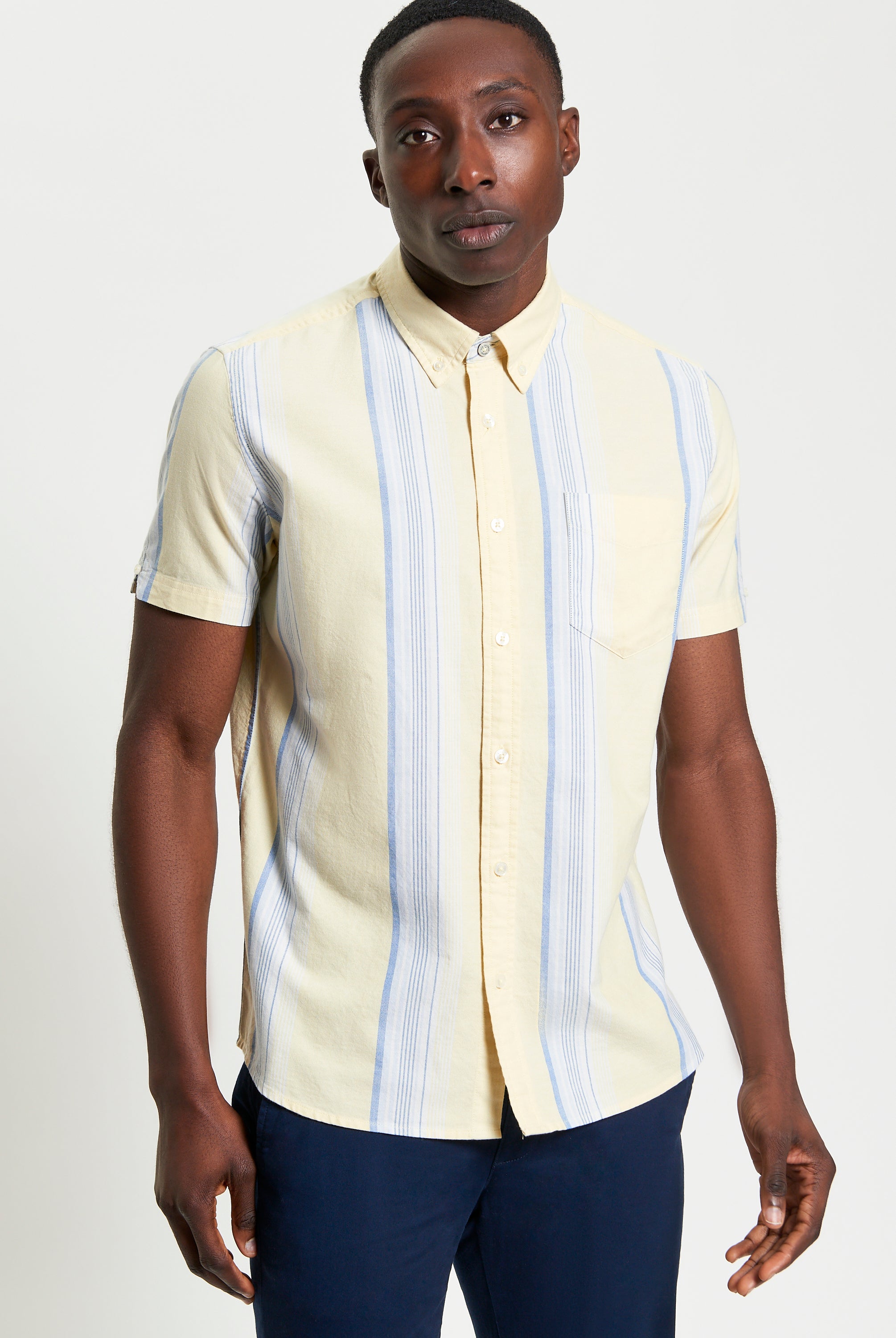 Oxford Stripe β short sleeve shirt with yellow and blue stripes, featuring a button-down collar and chest pocket.