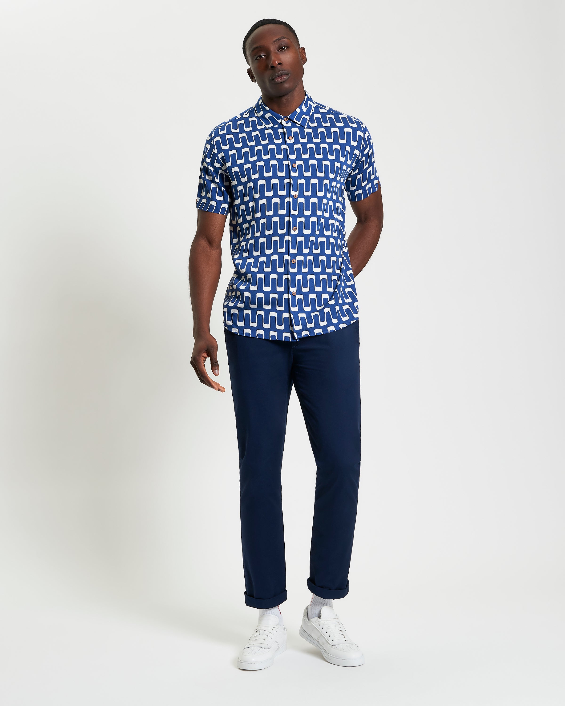 Jazz Print short sleeve shirt with abstract wave pattern, styled with navy trousers and white sneakers.