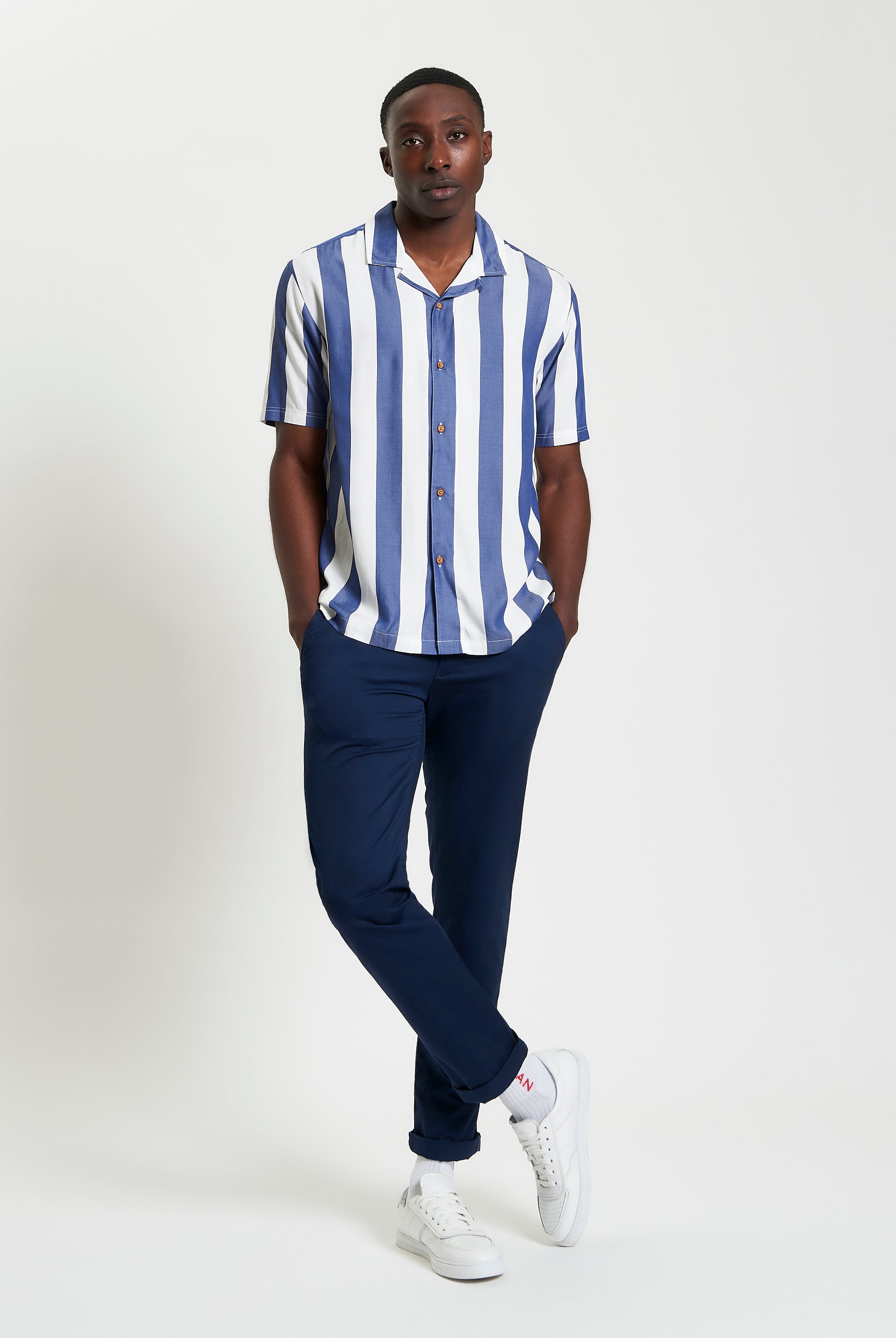 Viscose Stripe Shirt worn by a model, featuring short sleeves, revere collar, and relaxed fit, paired with navy pants.