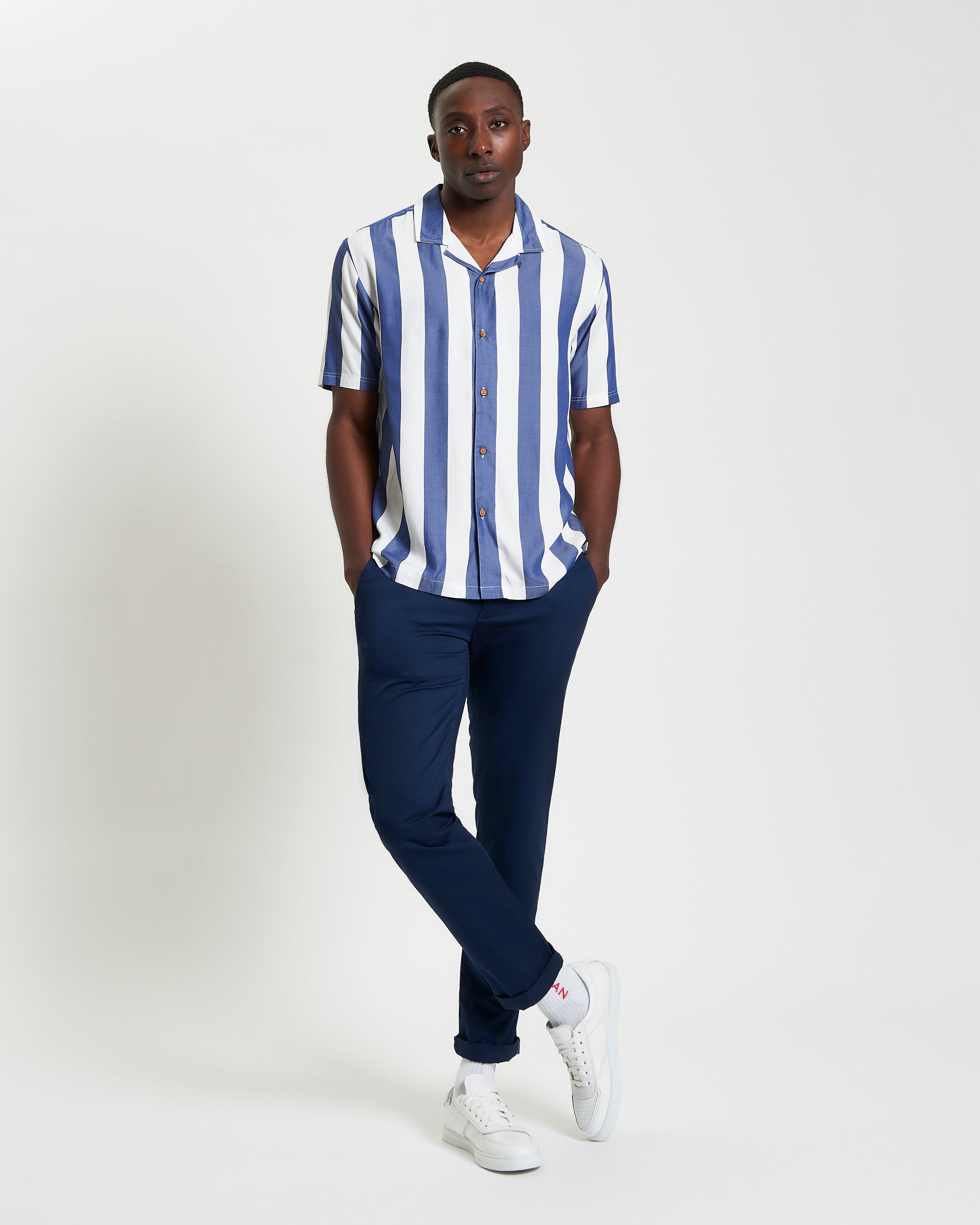 Viscose Stripe Shirt worn by a model, featuring short sleeves, revere collar, and relaxed fit, paired with navy pants.