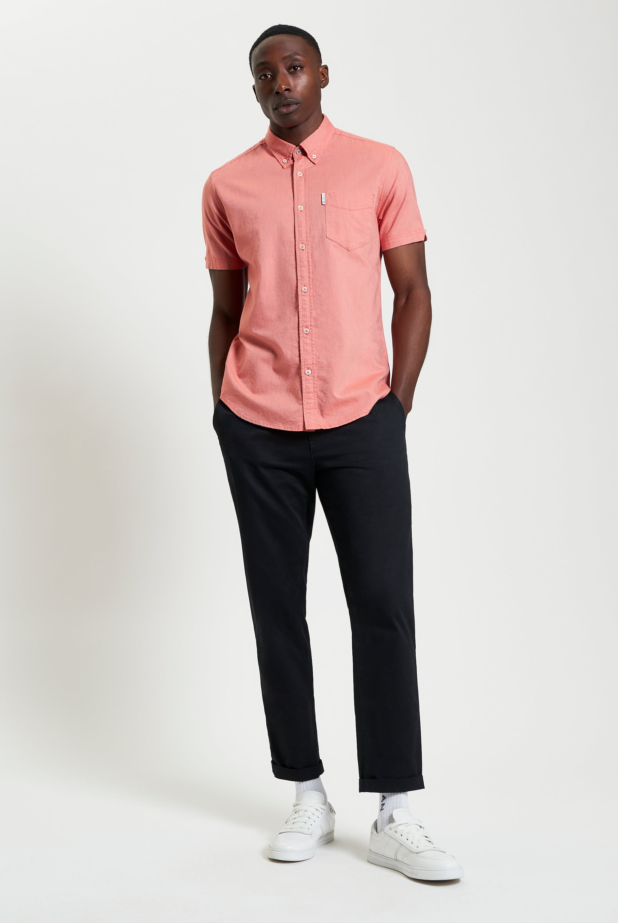 Model wearing Signature Oxford Short Sleeve Shirt in coral, styled with black pants for a modern look.