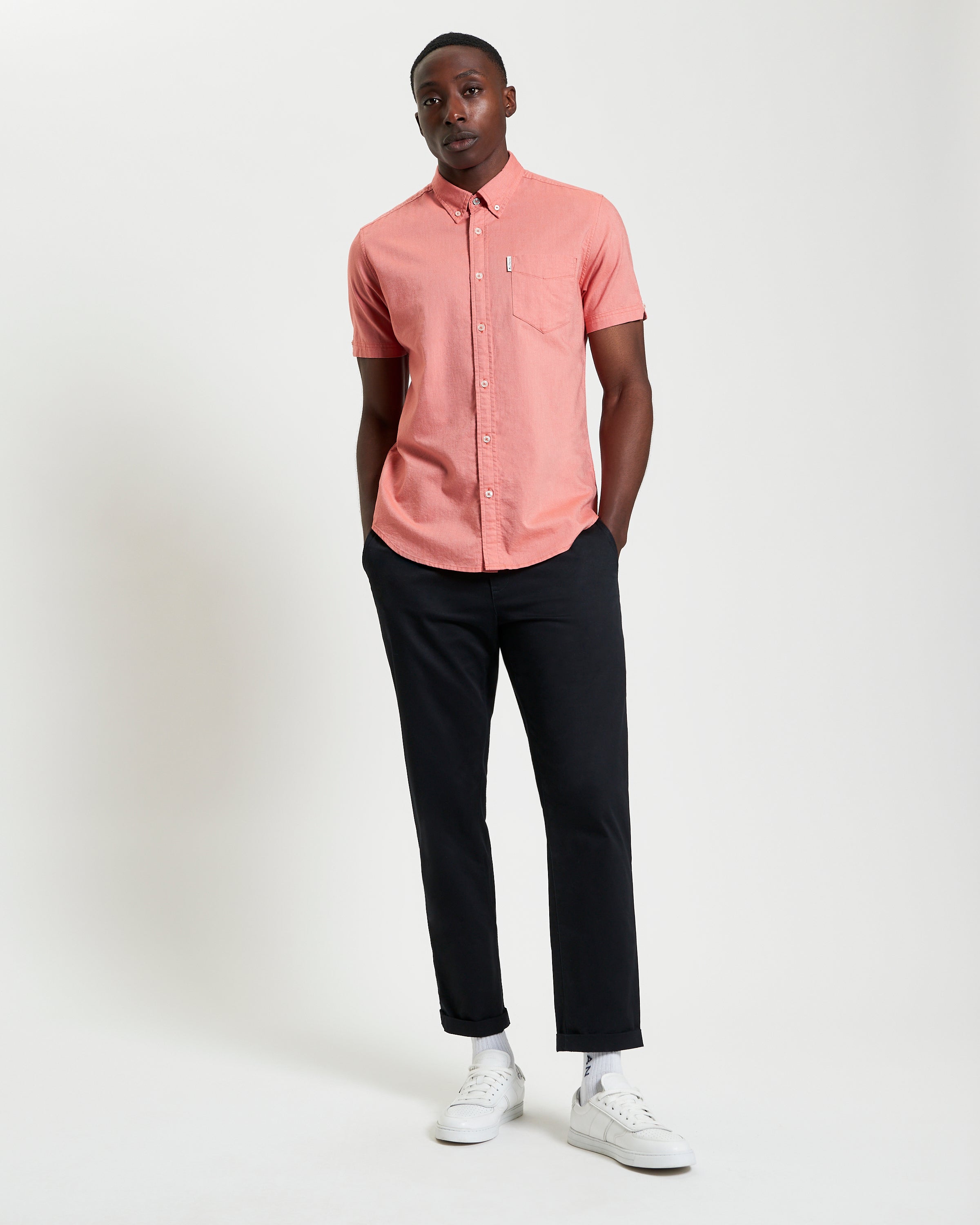 Model wearing Signature Oxford Short Sleeve Shirt in coral, styled with black pants for a modern look.