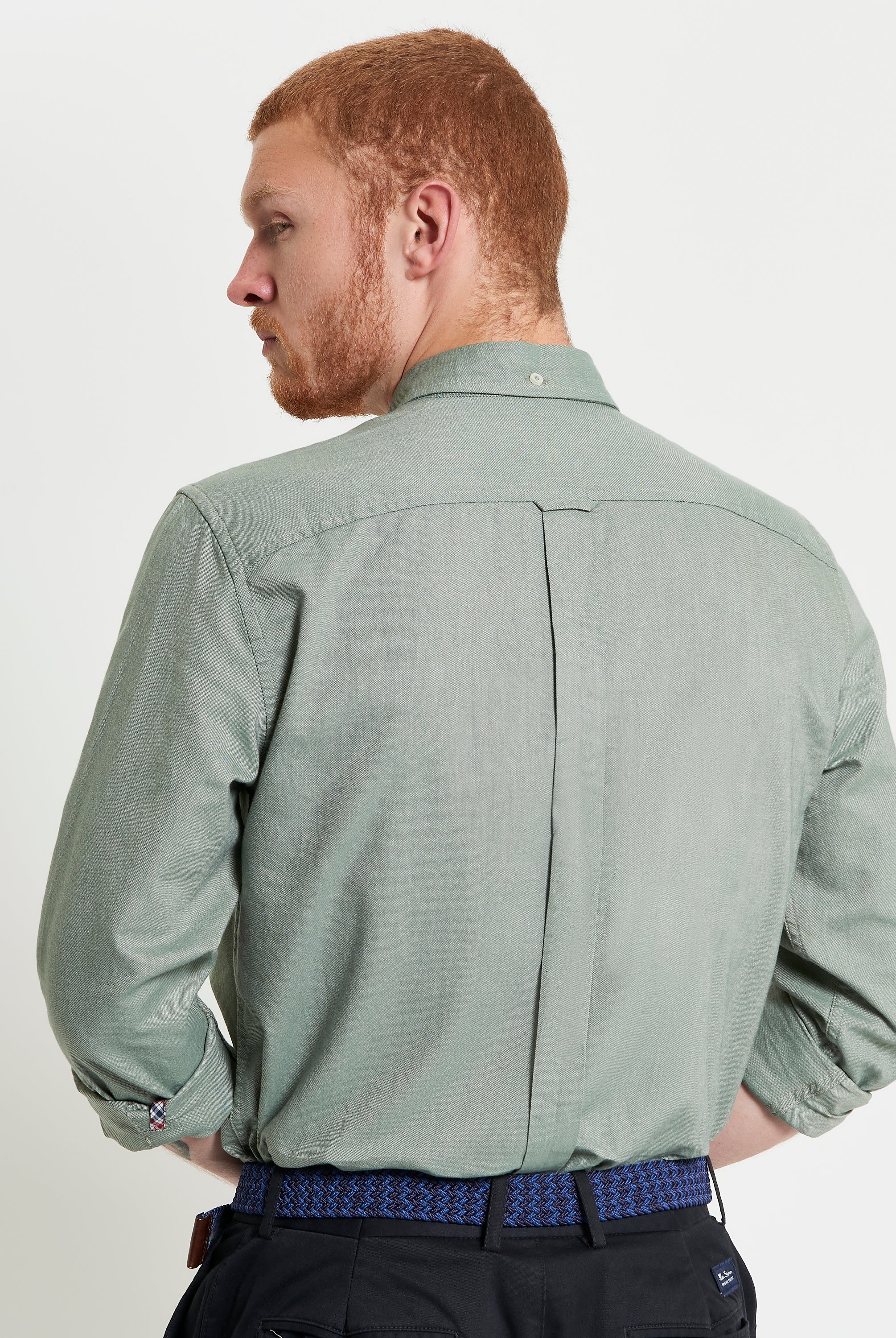 Back view of a man wearing a Signature Oxford Long Sleeve Shirt in green, showcasing the two-finger collar and back box pleat.