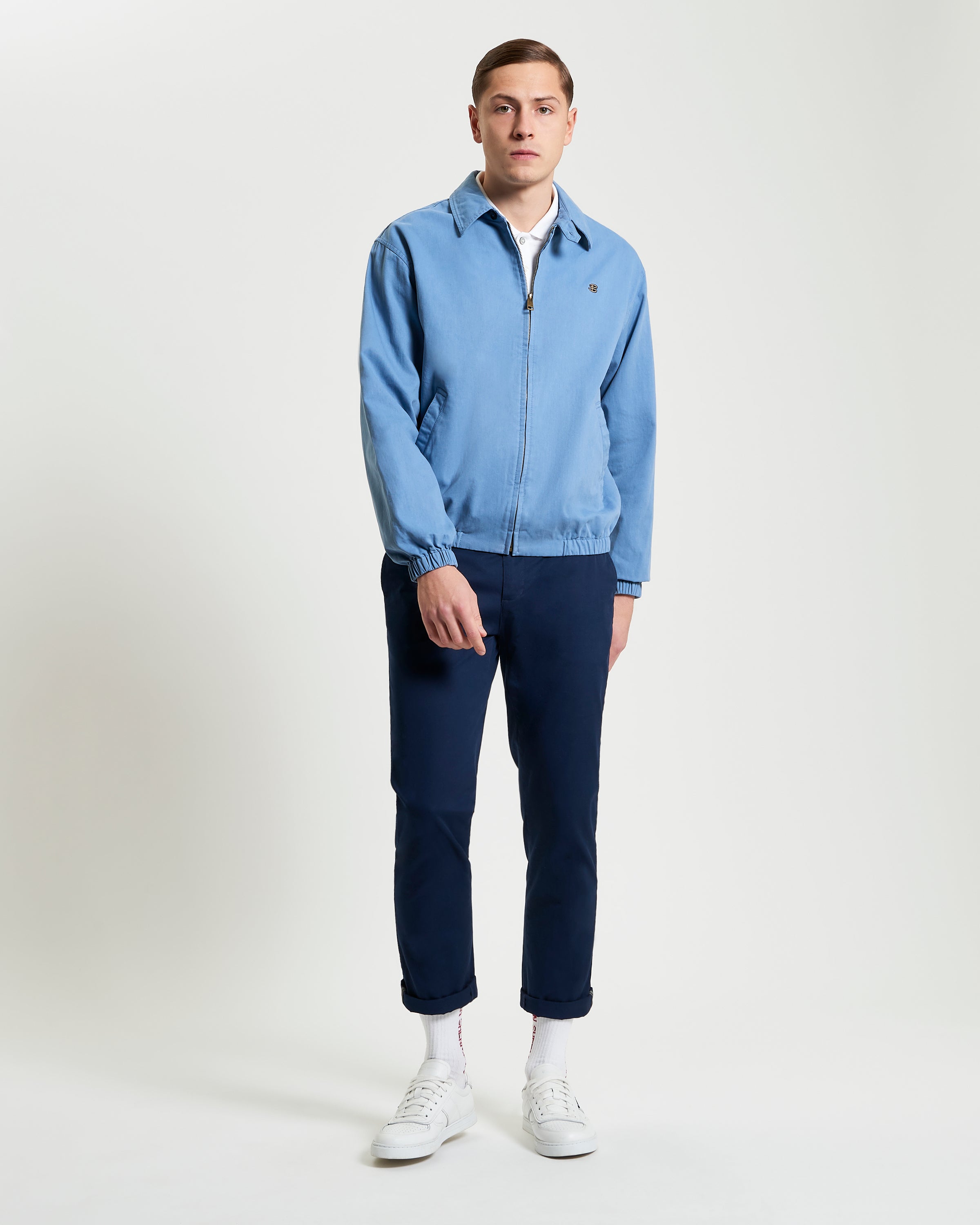 Sports Blouson – blue zip-up jacket worn by a model, featuring elasticated cuffs and two external pockets.