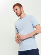 Signature Tee – light blue crew neck shirt with branded silicon badge, perfect for lounging or casual outings.