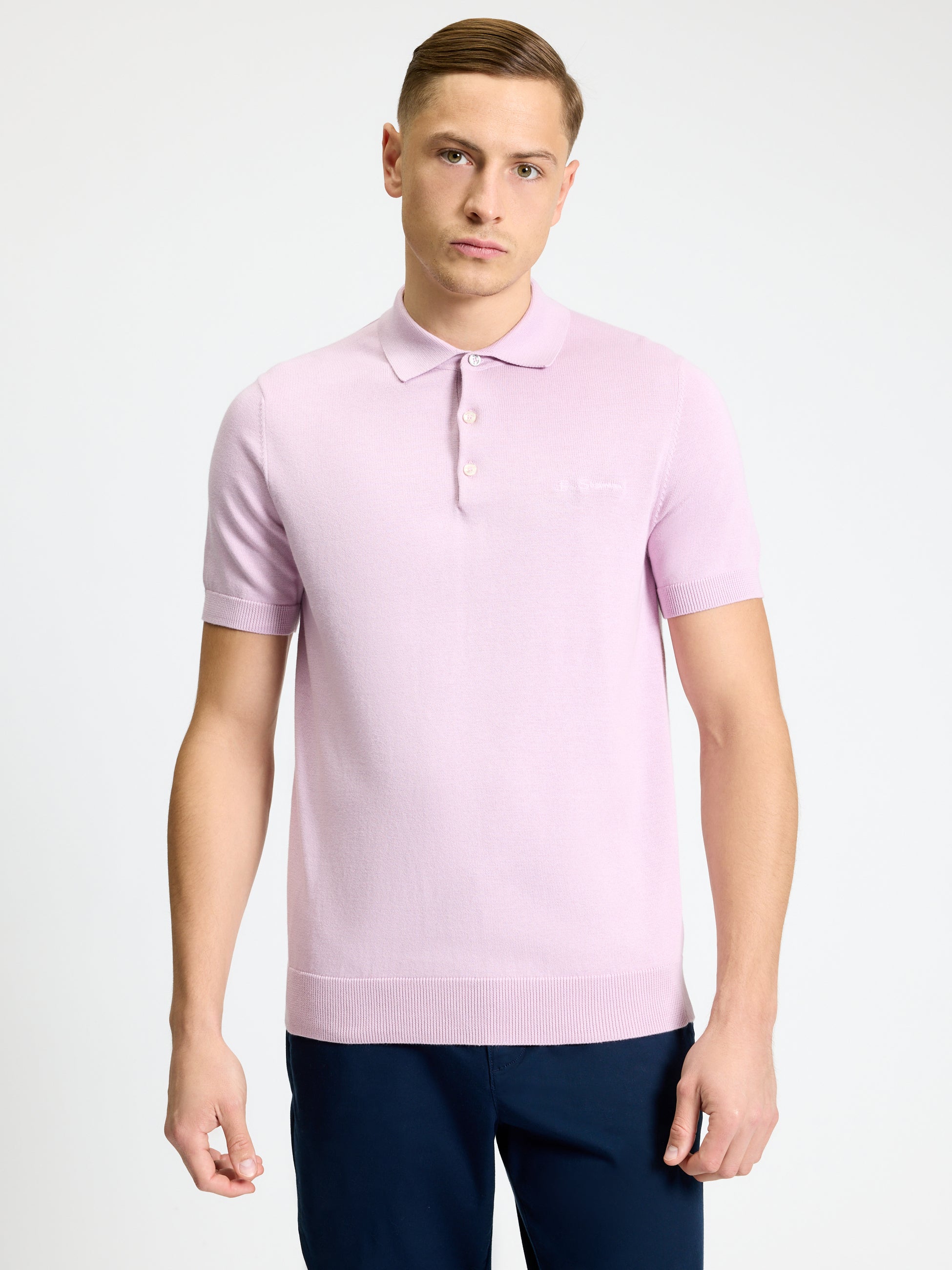 Signature Short Sleeve Polo in soft pink color, featuring ribbed collar and clean two-button placket, modeled by a young man.