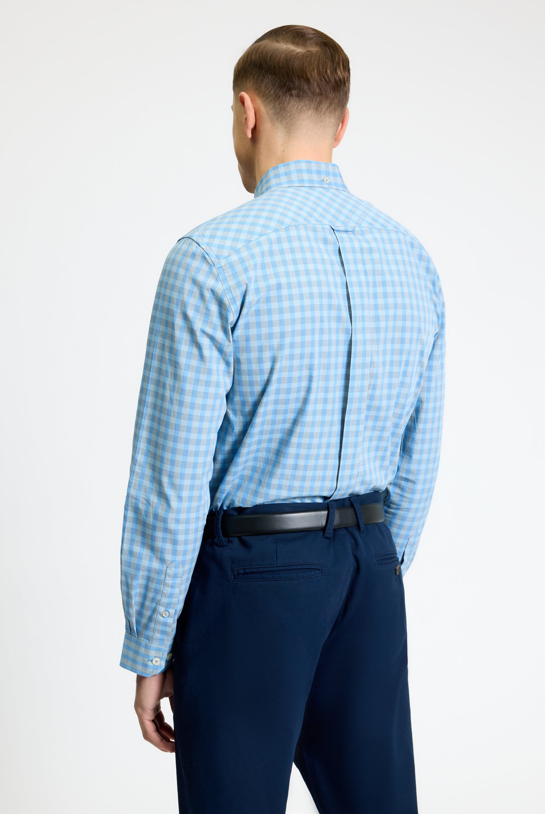 Back view of a man wearing a Linear Gingham Shirt by Ben Sherman, featuring a blue gingham pattern and curved hem.