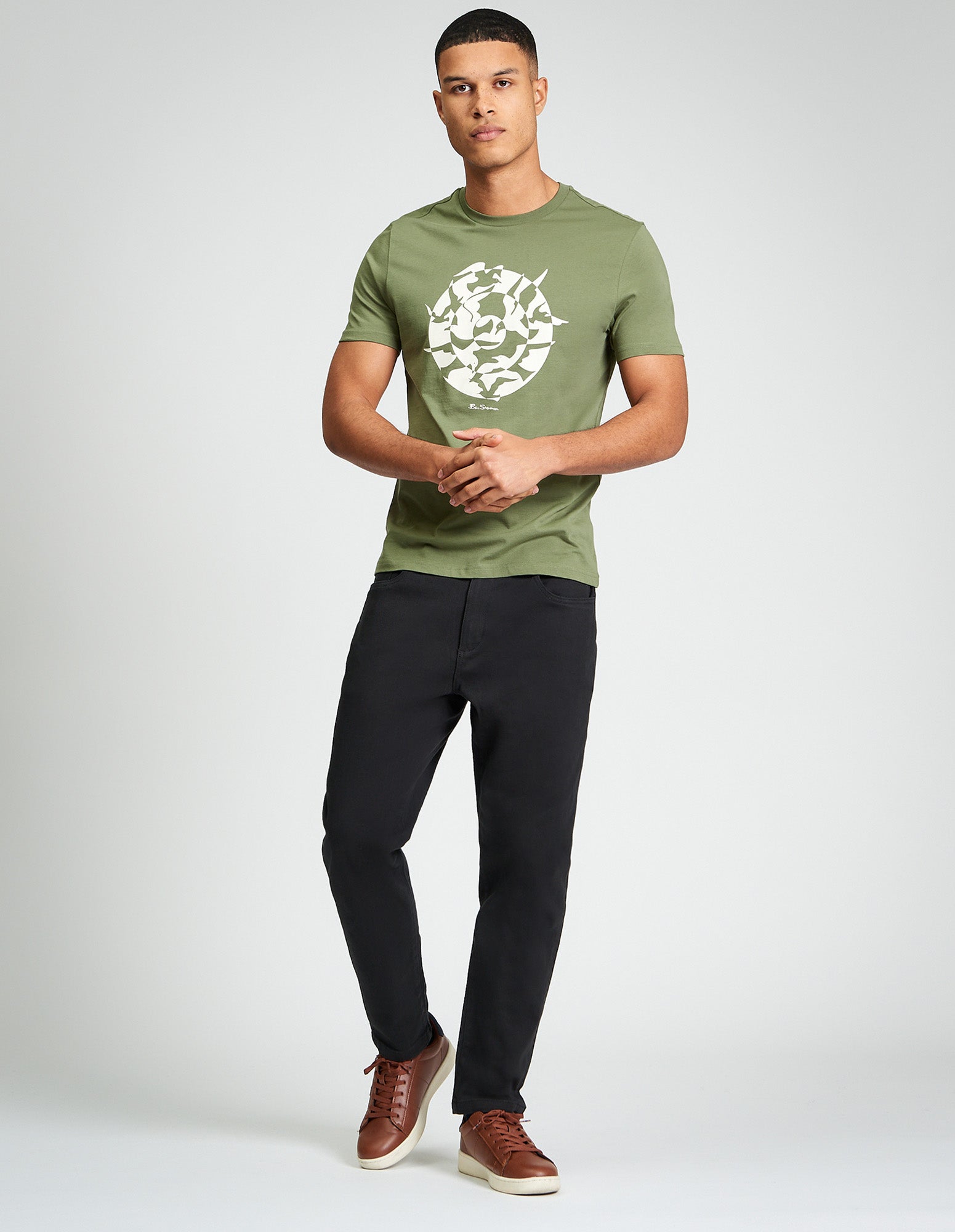 Man wearing Seagull Target Tee in olive green with seagull graphic design, paired with black pants and brown sneakers.