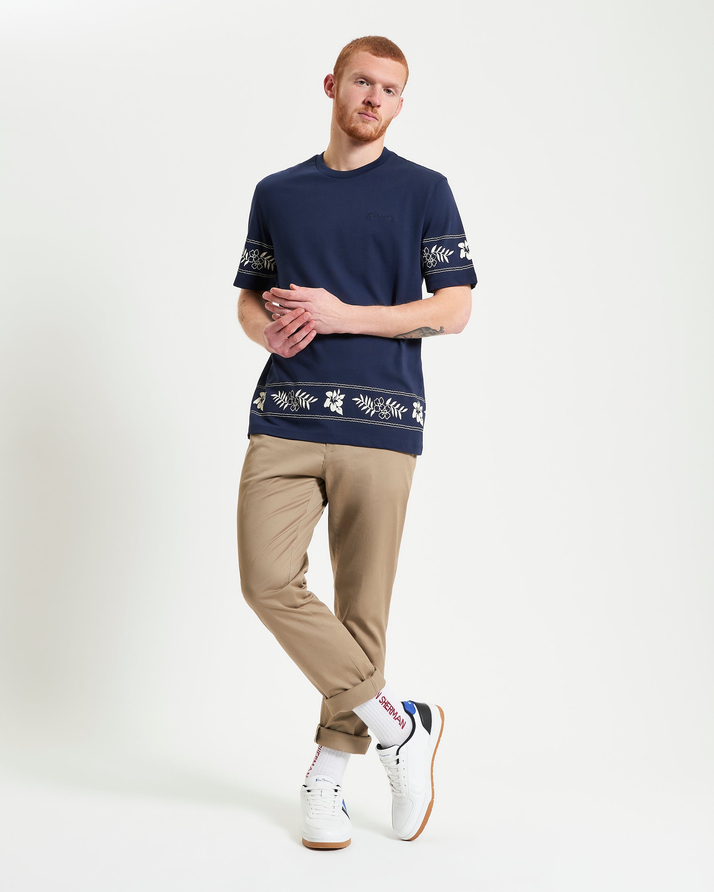 Border Print Tee – navy blue with floral border print worn with light khaki pants.