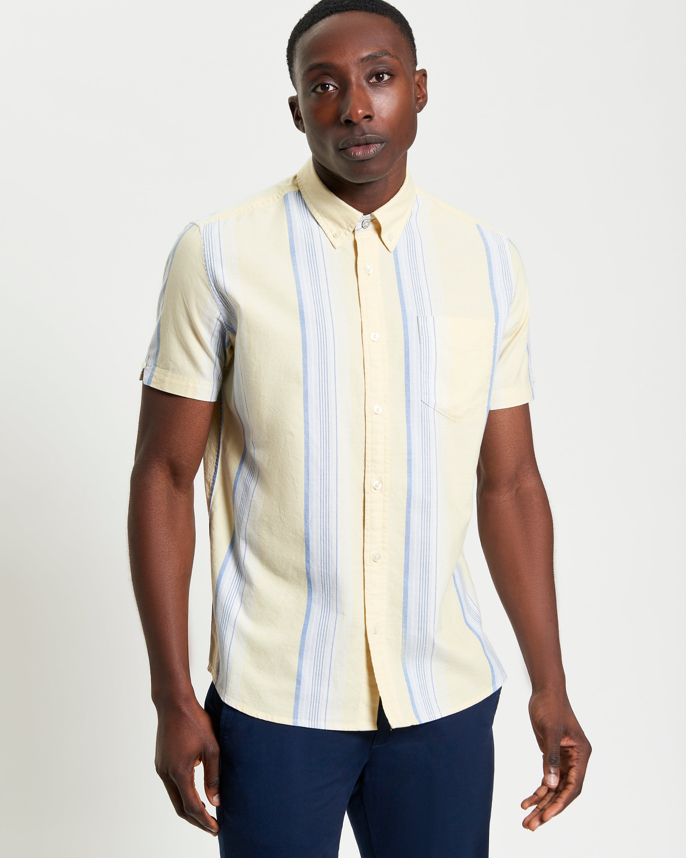 Oxford Stripe – short sleeve shirt with yellow and blue stripes, featuring a button-down collar and chest pocket.