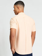 Signature Oxford Short Sleeve Shirt – back view of a man wearing a peach-colored shirt showcasing the back box pleat.