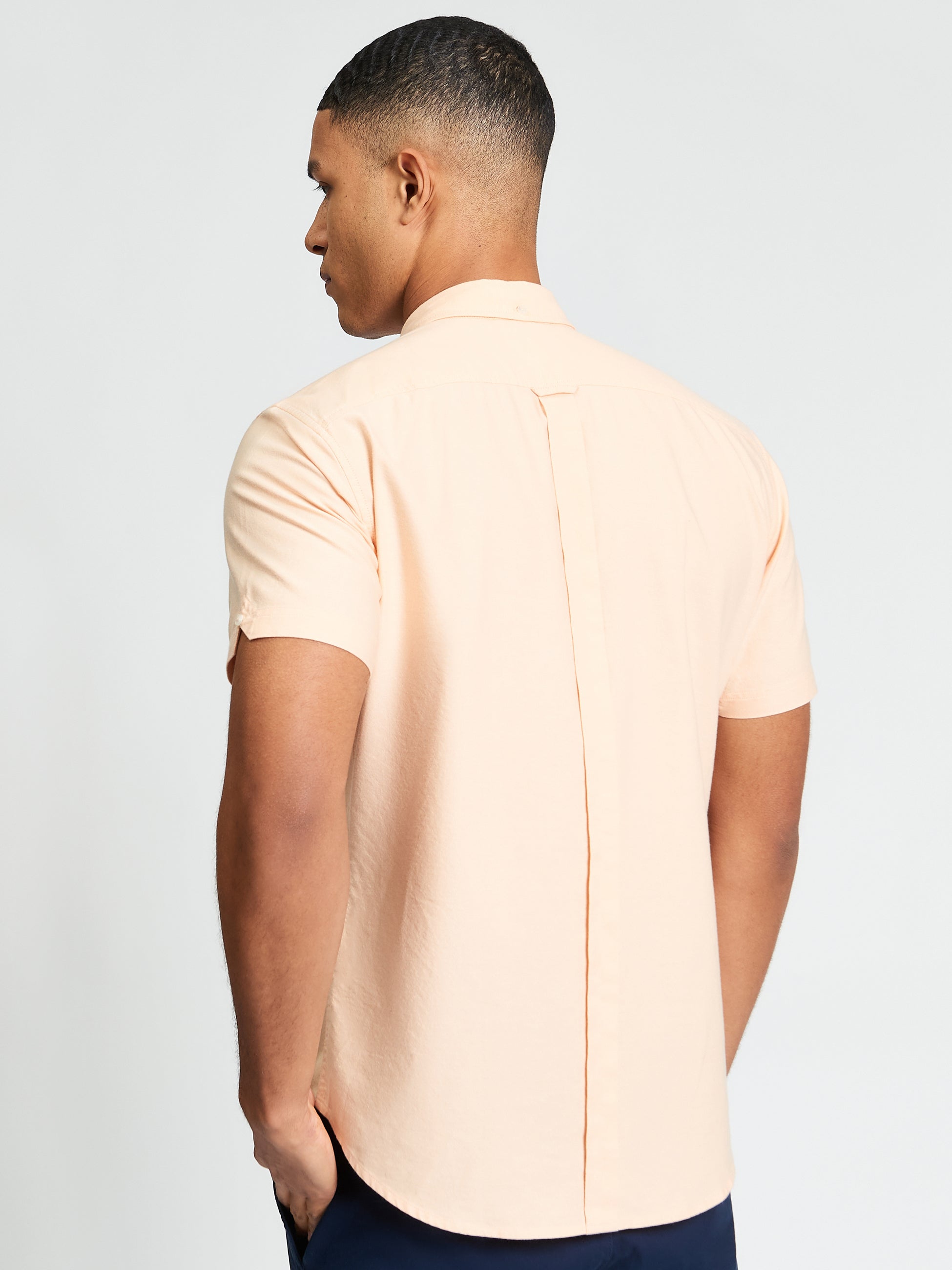 Signature Oxford Short Sleeve Shirt – back view of a man wearing a peach-colored shirt showcasing the back box pleat.
