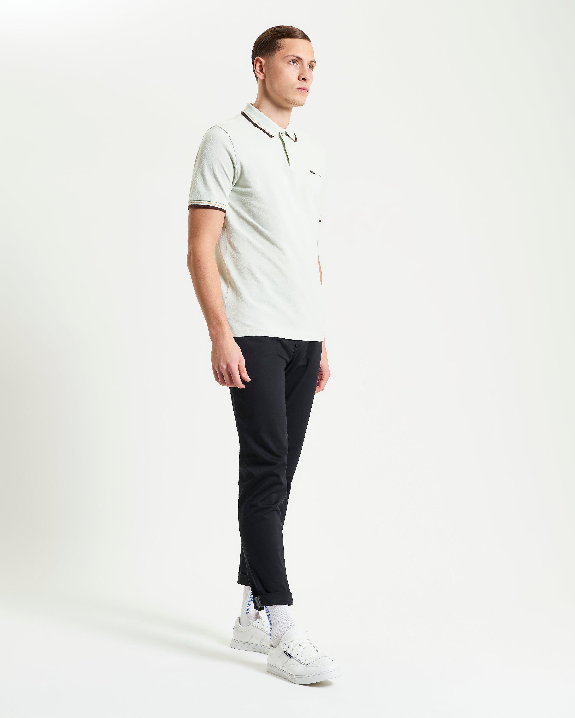 Signature Pique Polo – model wearing a light green polo with contrasting details and black pants, showcasing refined casual style.
