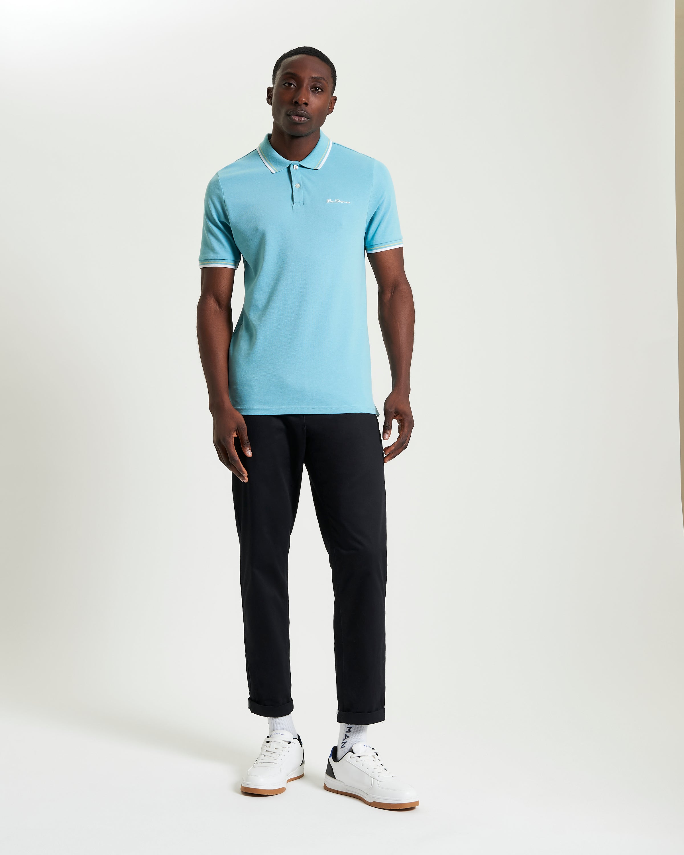 Signature Pique Polo – blue polo shirt worn by a man in casual outfit with black pants and white sneakers.