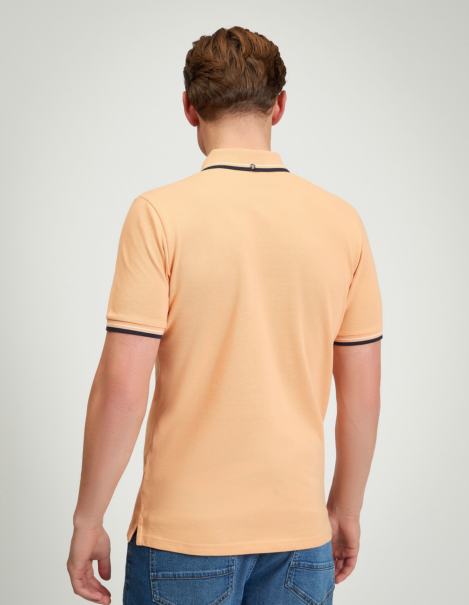 Signature Pique Polo – back view of a man wearing a peach polo shirt with contrast detailing.