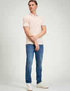 Model wearing Signature Pique Polo in pink, showcasing refined casual style with jeans.