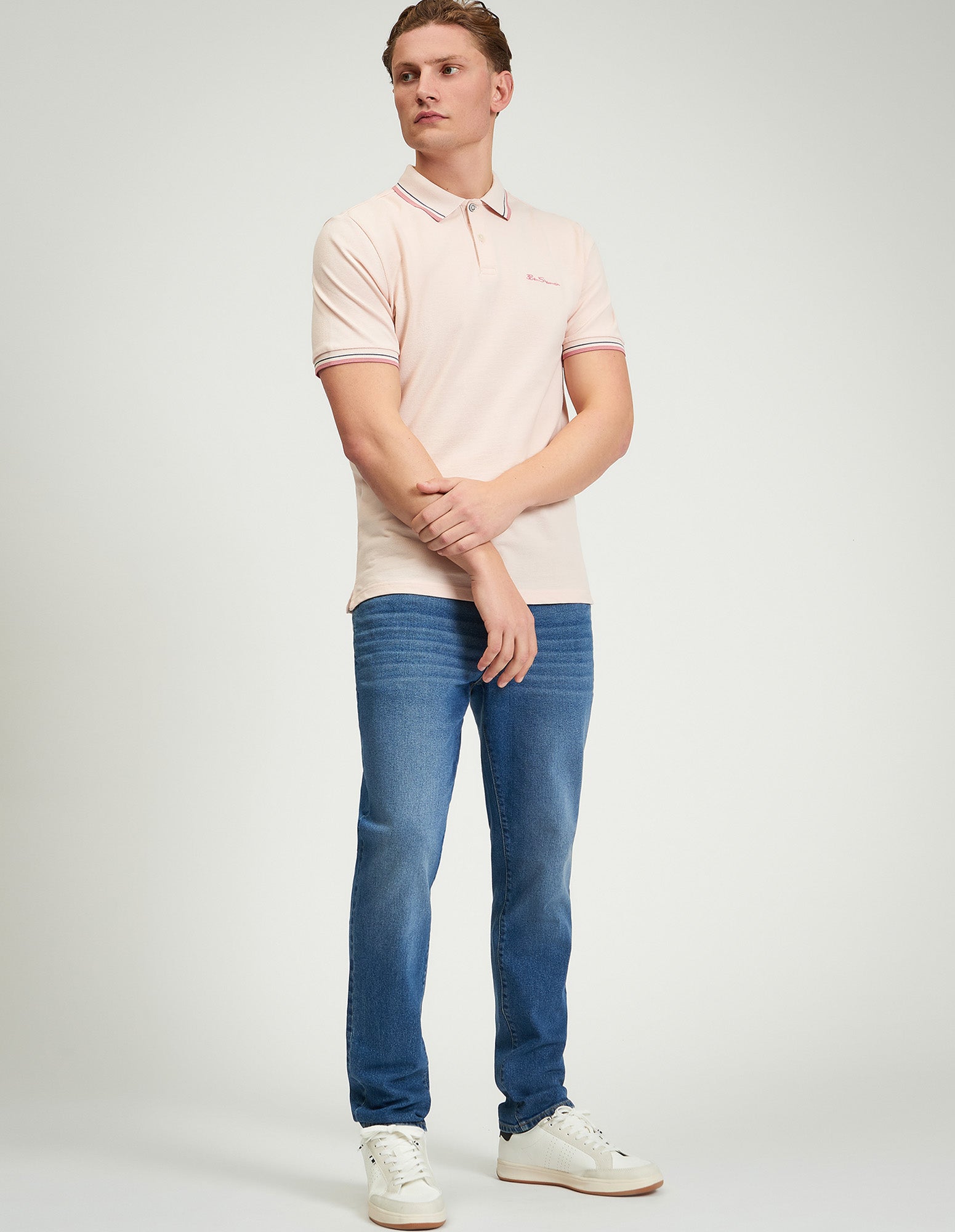 Model wearing Signature Pique Polo in pink, showcasing refined casual style with jeans.