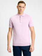 Signature Short Sleeve Polo in soft pink color, featuring ribbed collar and clean two-button placket, modeled by a young man.