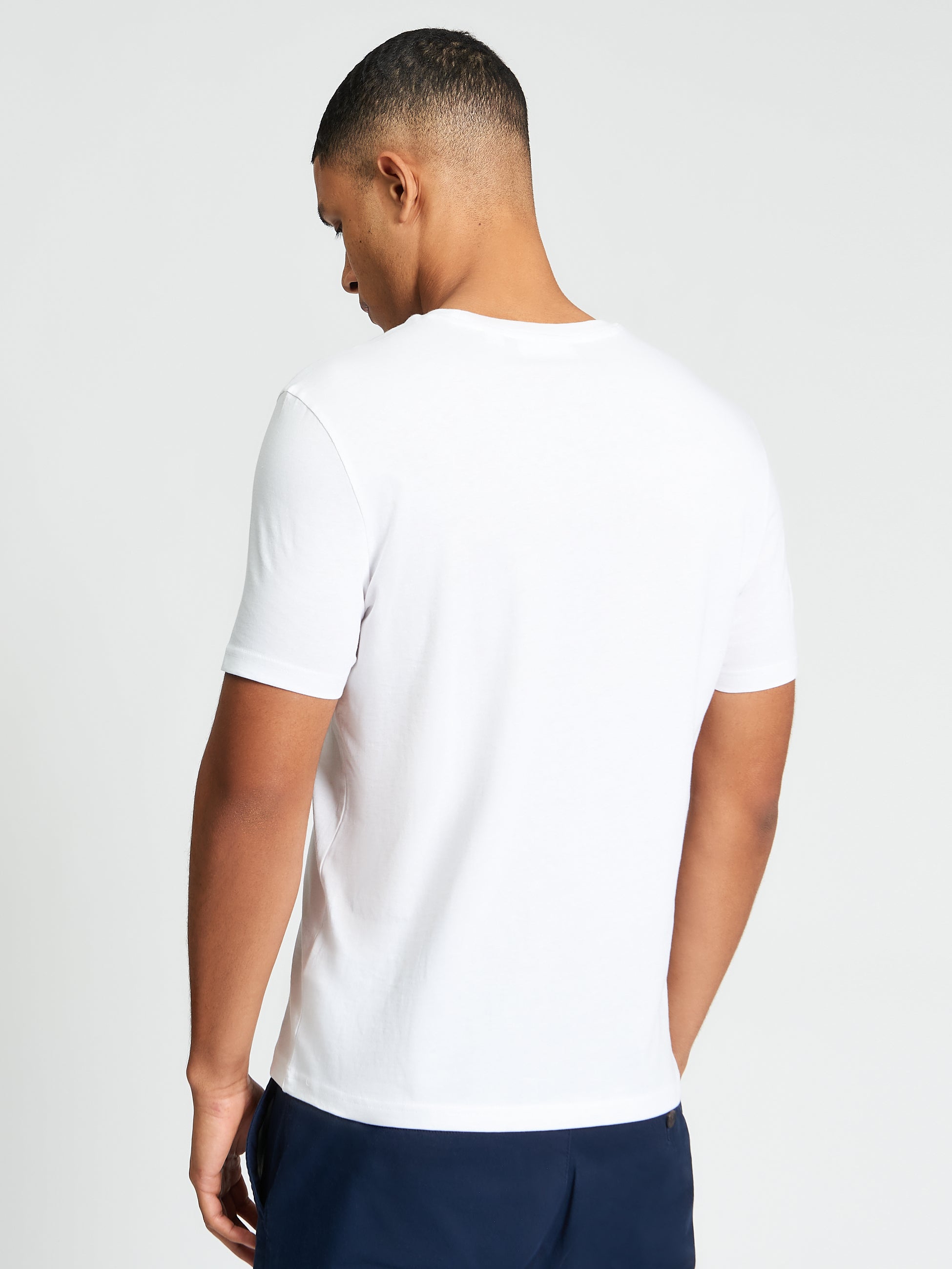 Core Stripe Tee – Back view of a man wearing a white tee crafted from 100% organic cotton.