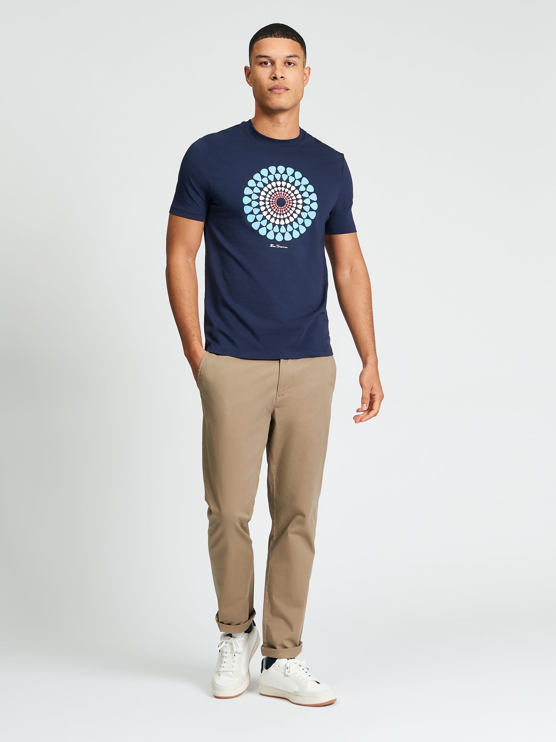 Man wearing Plectrum Target Tee by Ben Sherman with target graphic, paired with chinos and sneakers.