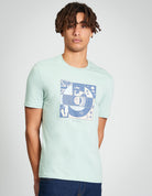 Comic Target Tee – summer graphic print on a green t-shirt, made from 100% organic cotton, worn by a male model.