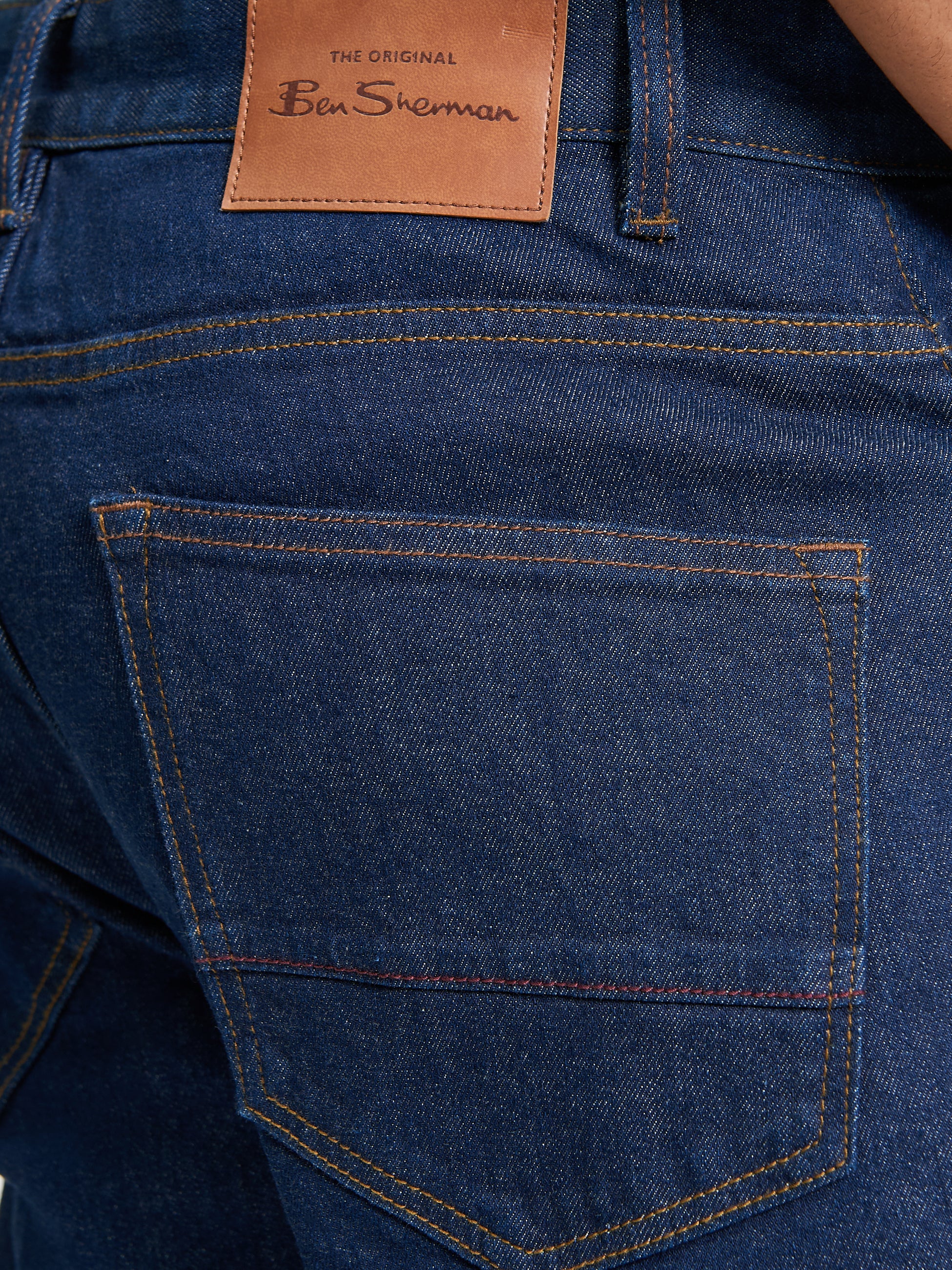 Slim Taper Denim – close-up of back pocket and branded patch detail.