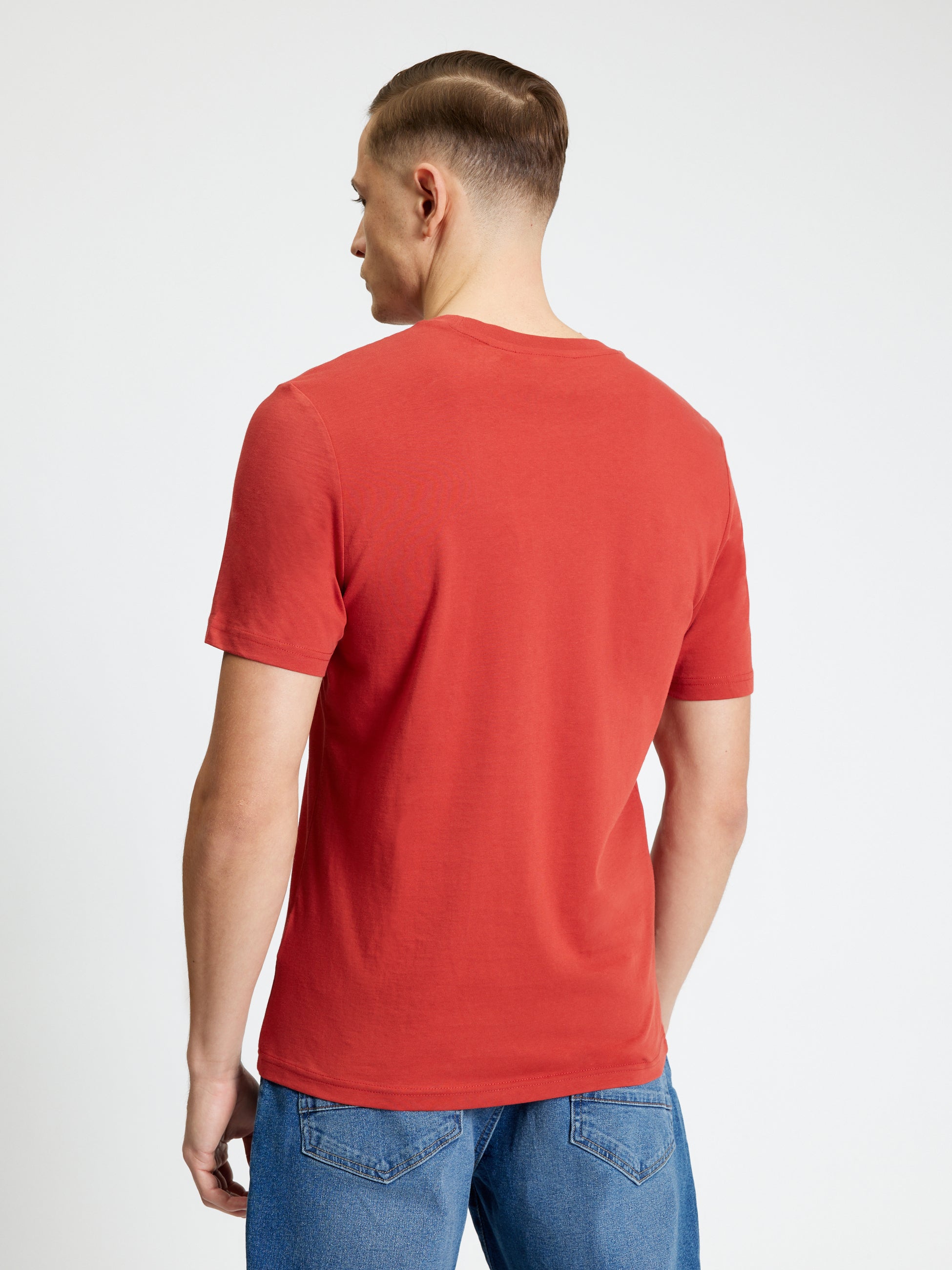 Back view of a man wearing a red Signature Tee, showcasing its regular fit and crew neck design.