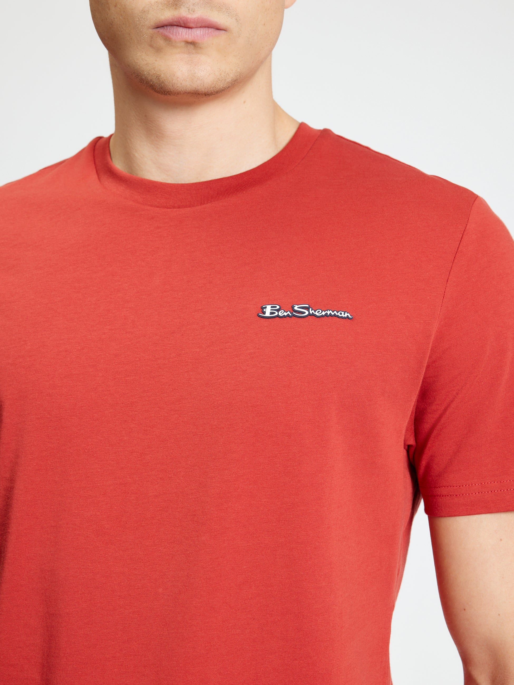 Signature Tee – red crew neck t-shirt with branded badge for casual wear.