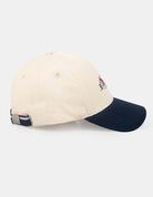 CONTRAST PEAK HAT - beige and navy cap with logo, side view.